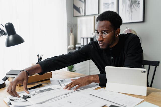 Person reaching for documents across a desk with a tablet next to them